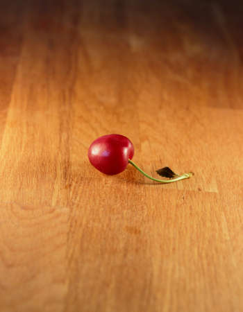 A cherry on a wooden table