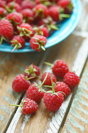 Red raspberry in blue dish on old vintage wooden table.の写真素材