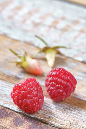 Two red raspberry on old vintage wooden table.