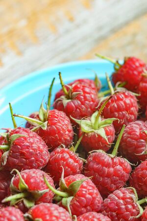 Red raspberry in blue dish on old vintage wooden table.の写真素材