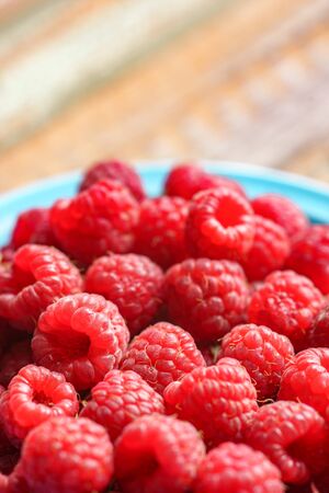 Red raspberry in blue green dish on old vintage wooden table.の写真素材