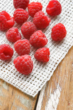 Red raspberry in front of white fabric on old vintage wooden table.の写真素材