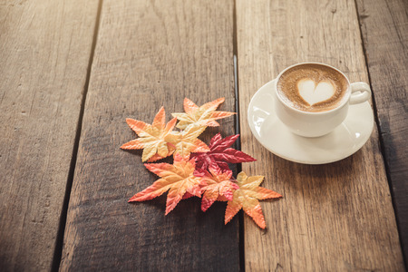 coffee cup on table,valentine with hot coffee and heart shape on top of cup on wood table,love valentine with color foliage leafs and coffee cup on tableの写真素材