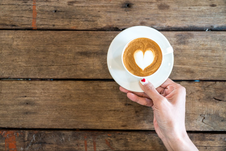 hands holding coffee cup,heart on coffee cup and woman nails,valentine love concept.の写真素材