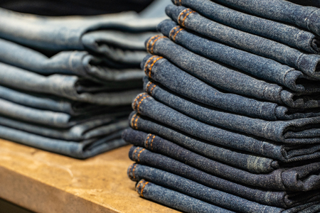 stack of various shades of blue jeans.Denim clothing background.の写真素材