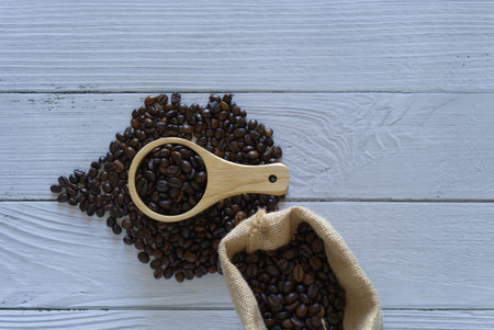 Coffee beans isolated and scoop sack bag on white wooden backgroundの写真素材