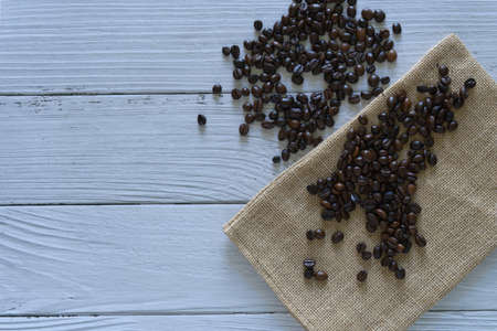 Coffee beans isolated with sack bag on right side white wooden background.jpgの写真素材