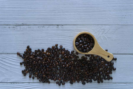 Coffee beans isolated with scoop on white wooden background