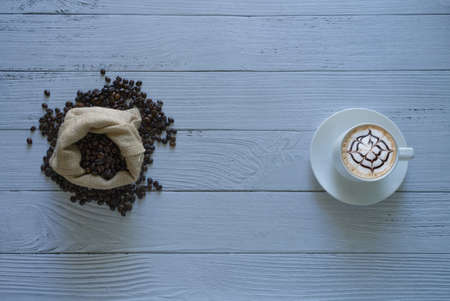 Coffee beans isolated with sack bag and latte art coffee in a coffee cup top view isolater on white...
