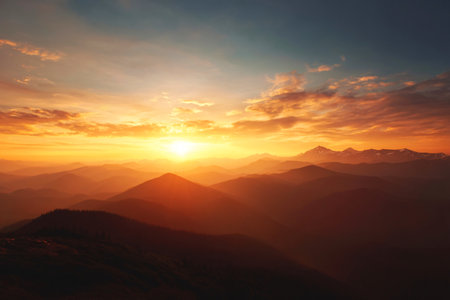 sunset over mountain ridge with glowing sky, atmospheric nature background, warm color paletteの素材