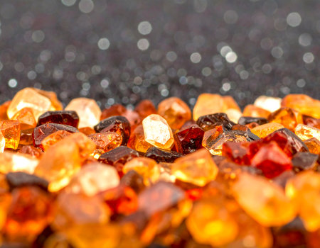 Glittery dark grey background decorated with orange and gold crystalsの素材