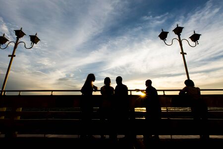 Silhouettes of people standing along the road.
