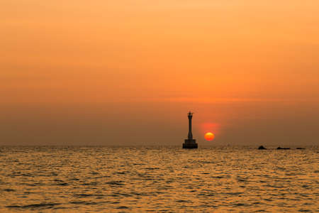 Silhouette of lighthouse at sunrise.