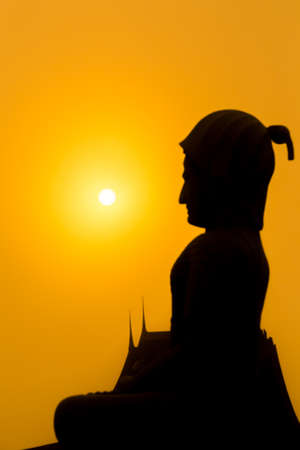 Buddha silhouette with the sun at sunset. Focus on the sun.の写真素材