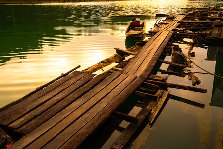 Sunset over the reservoir with a wooden bridge and boaの写真素材