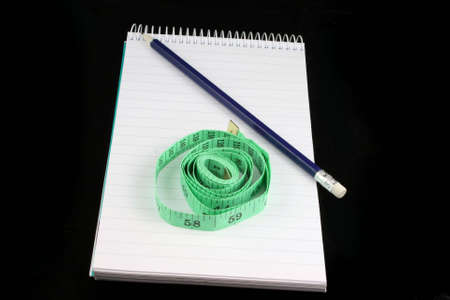 Notepad, pencil, and tape measure on a black backgroundの写真素材