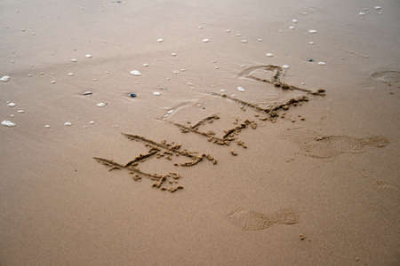 The word Help written in sand next to the shoreの写真素材