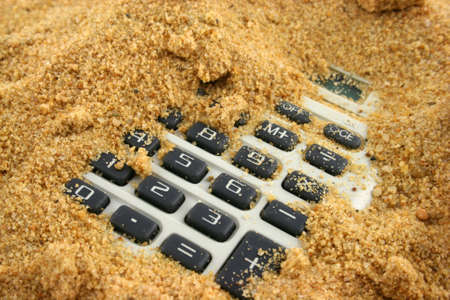 A calculator buried in the sand - buttons showingの写真素材