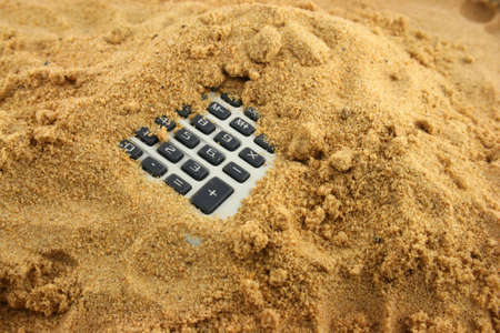 A Calculator half buried in the sand の写真素材