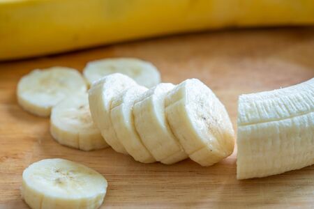 Slices banana on a cutting board.Chopped  fresh banana get vitamin.close up yellow tropical fruit.の写真素材