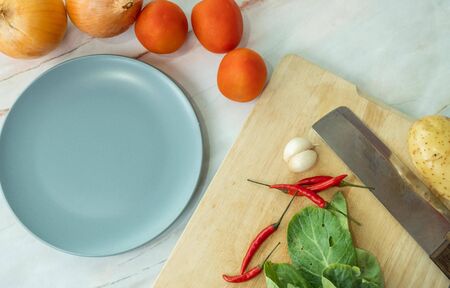 Ingredient are aound copy space.Cutting board with knife chilli tomato potato galric onion dish are...