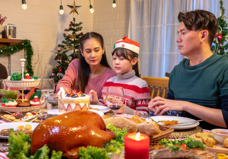 Happy people are celebrating on a table meal when christmas and new year at home. Cheerful elder , daughter ,son and child are eating dinner food with merry xmas decoration when happy new year holiday.の写真素材