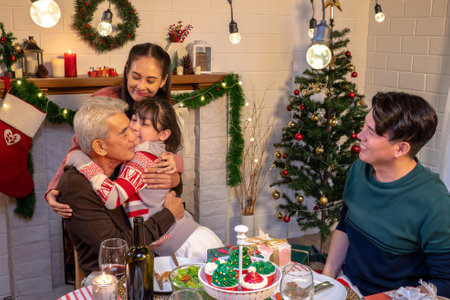 Happy people are celebrating on a table meal when christmas and new year at home. Cheerful elder , daughter ,son and child are eating dinner food with merry xmas decoration when happy new year holiday.の写真素材