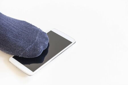 Feet of a man stepping on a dropped smartphoneの写真素材