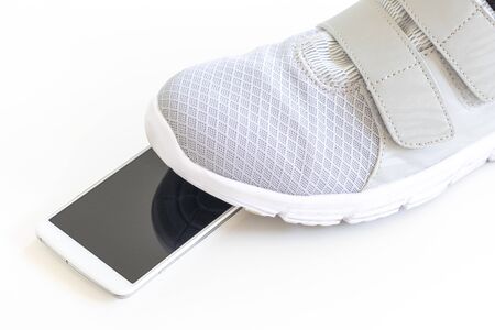 Feet of a man stepping on a dropped smartphone