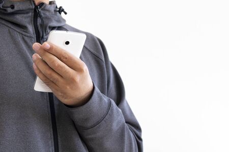 A man wearing a gray jersey operating a smartphoneの写真素材