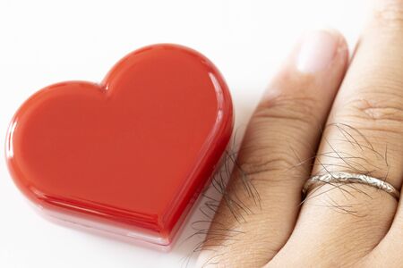Male hand with wedding ring and Heart figurine
