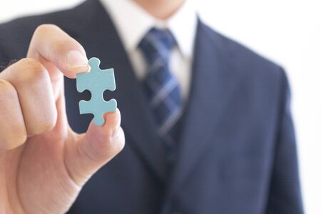 Men in suits holding jigsaw puzzle piecesの写真素材