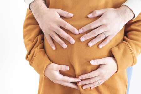 Hungry pregnant woman and her husband embracing herの写真素材