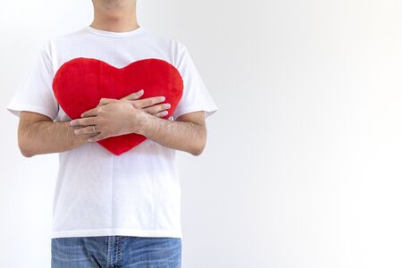 Man in white shirt with heart cushionの写真素材
