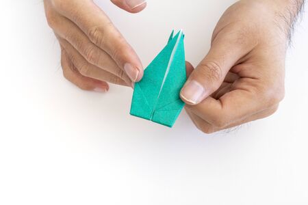 Hand of a man folding a crane with origamiの写真素材