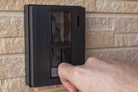 Man's hand bending his finger and pushing the button on the intercom