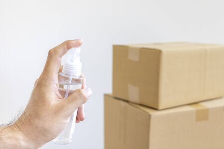 A man disinfects a cardboard box before opening with a disinfectant sprayの写真素材