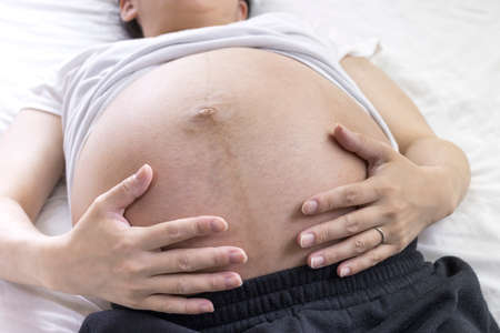 A pregnant woman near the expected date of birth lays in bed