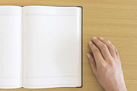 Man's hand writing with a pencil in an open notebookの写真素材