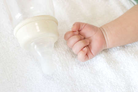 One month old baby hands and baby bottleの写真素材