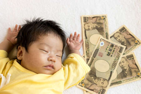 Sleeping baby and Japanese bills. Childcare cost imageの写真素材