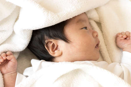 One month old baby wrapped in a towelの写真素材