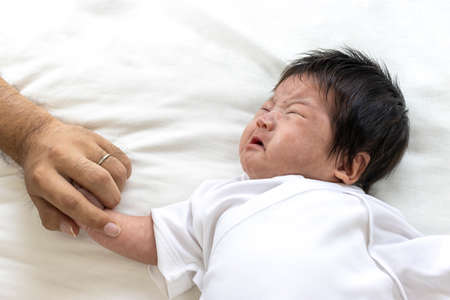Men's hands holding hands with a crying babyの写真素材