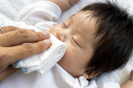 Man's hand wiping the baby's mouth with a clothの写真素材