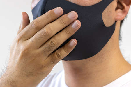 A man coughing in a black cloth mask