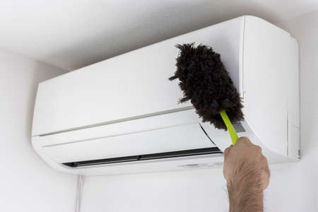 Hands of a man cleaning the exterior of an air conditioner with a handy mopの写真素材