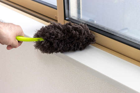 The hand of a man wiping the window with a handy mop