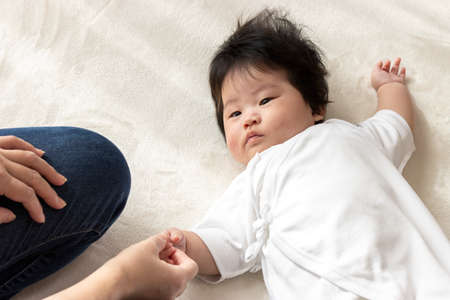 Woman holding hands with baby 0 years old, 4 months old, girlの写真素材