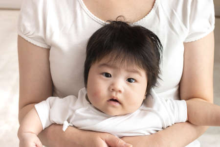 Mother in her 30s and baby sitting on her lap, 0 years old, 4 months old, girl