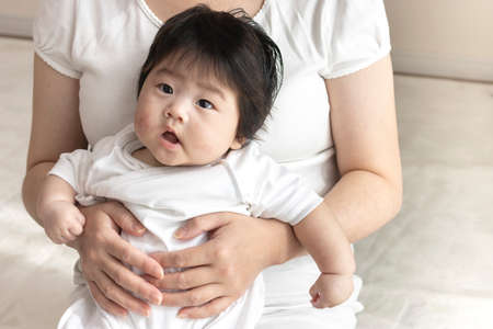 Mother in her 30s and baby sitting on her lap, 0 years old, 4 months old, girlの写真素材